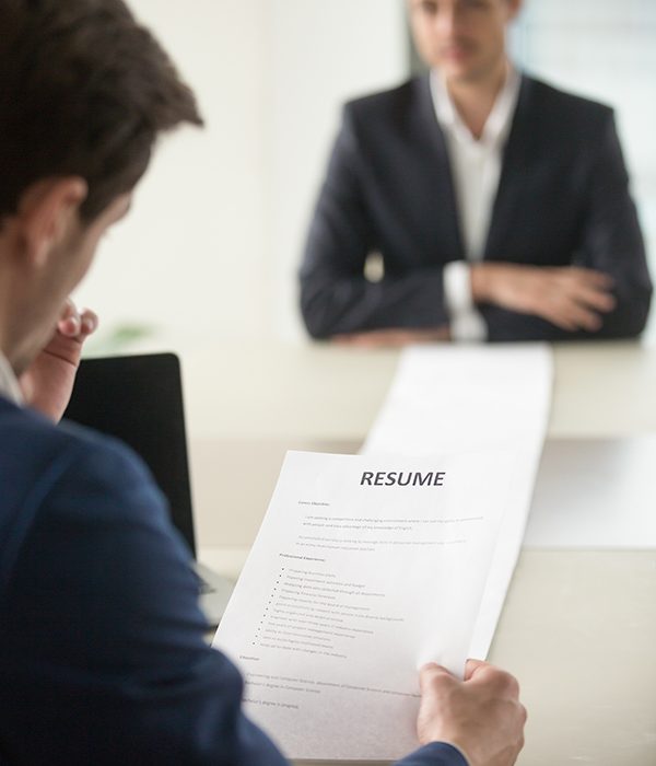 Interviewer reading applicants long resume Back view of employer reading resume focus on document, job applicant waiting for hiring decision at desk on background. Hiring manager studying long list of candidates achievements and experiences